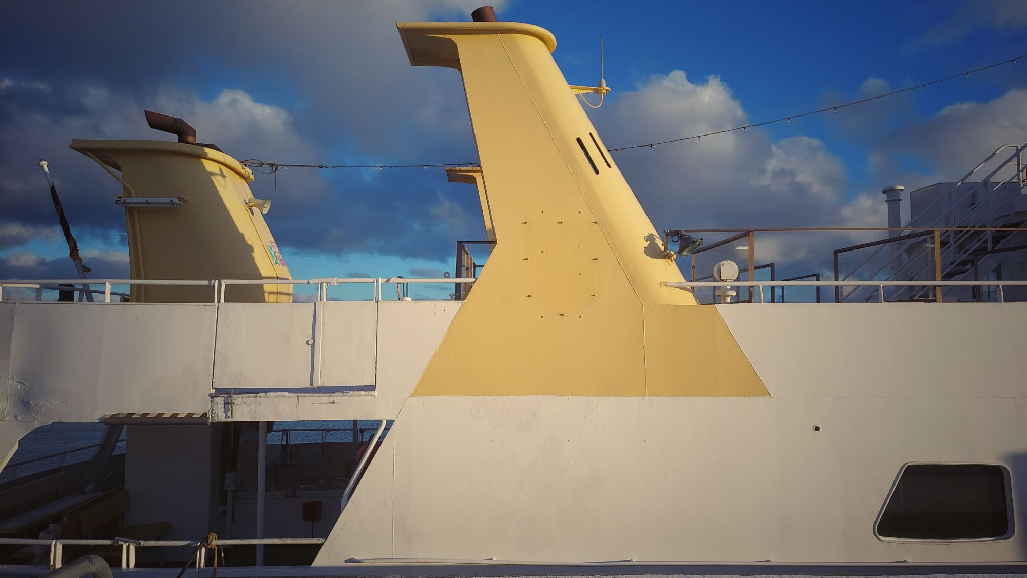 Chimneys and starboard side of a tourist ship in sundown light.