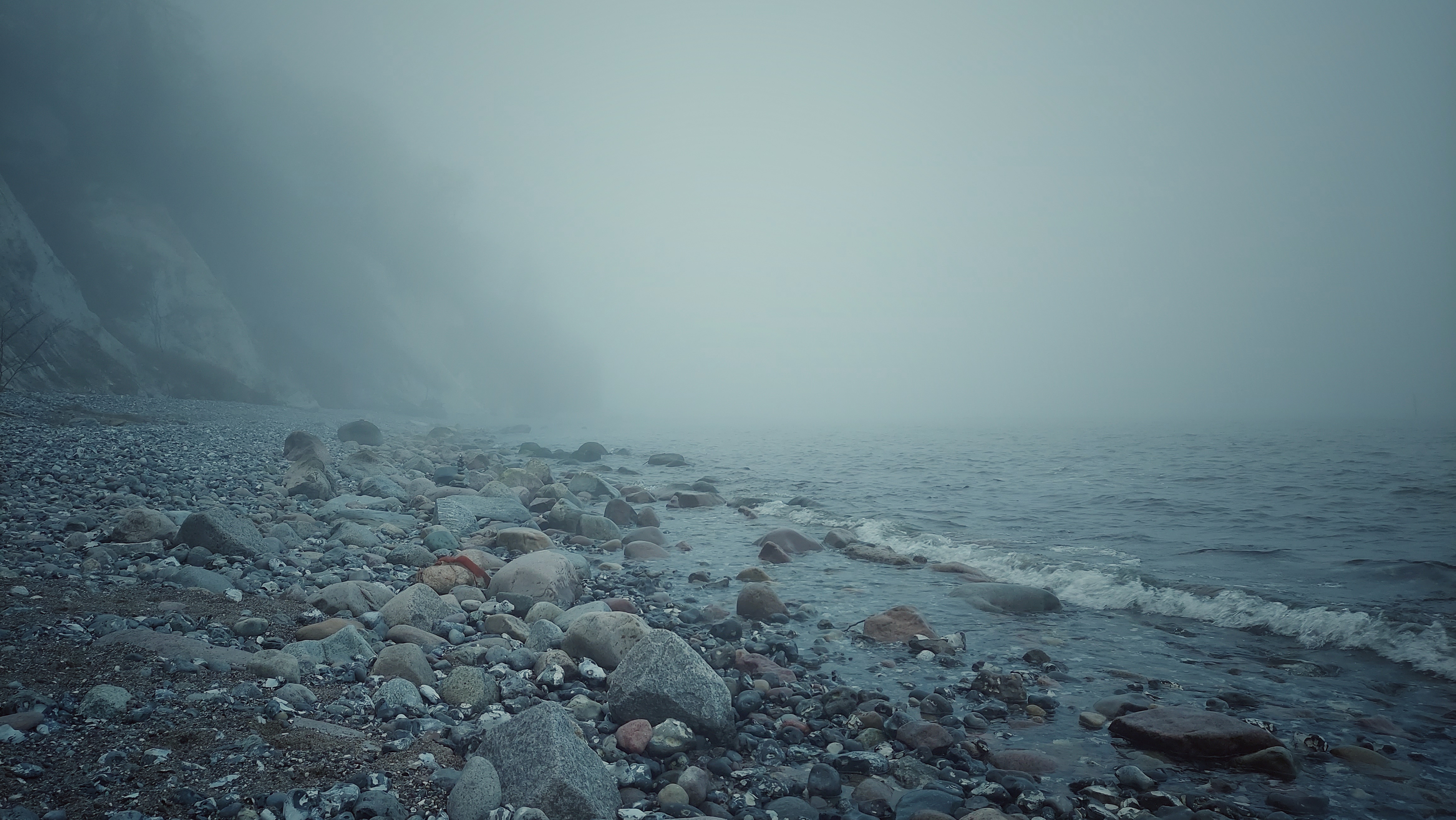 Foggy shores of the Baltic Sea. Waves on small rocks.