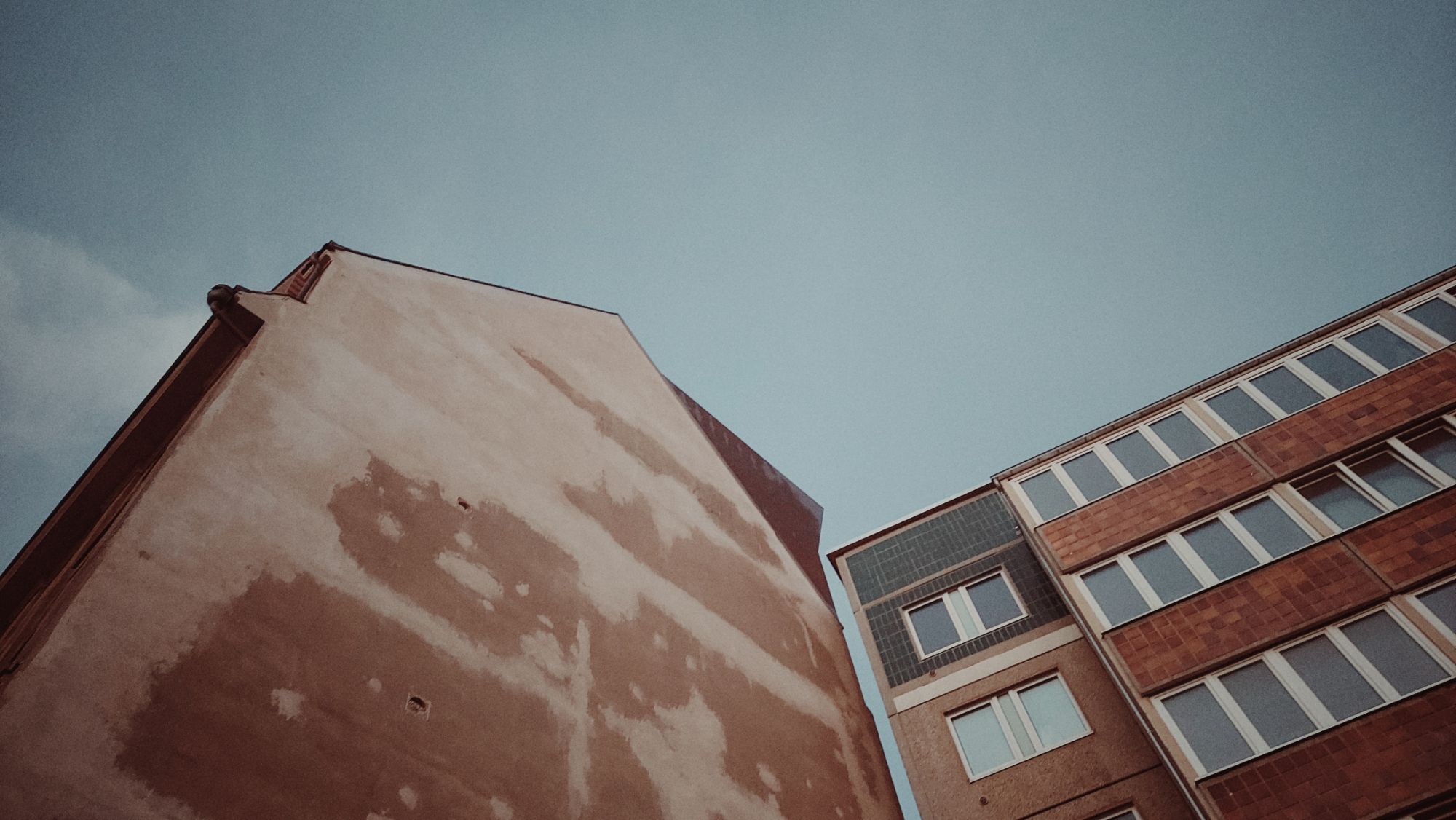 Facades of two different houses in front of blue sky